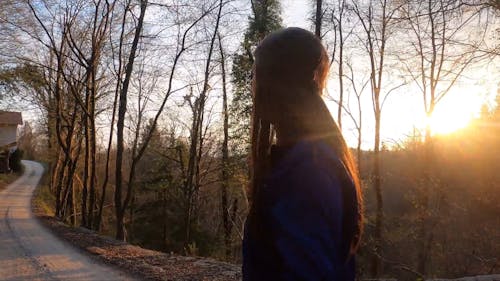 A Woman Walking In The Forest At Sunset