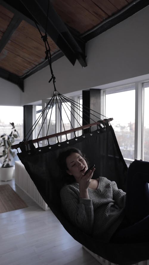 A Woman Resting In A Hammock While Talking On Her Cellphone