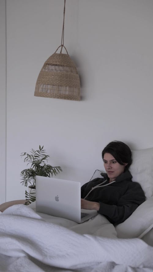 A Woman Typing on her Laptop in the Bedroom