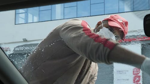 A Service Station Attendant Cleaning A Car Windshield