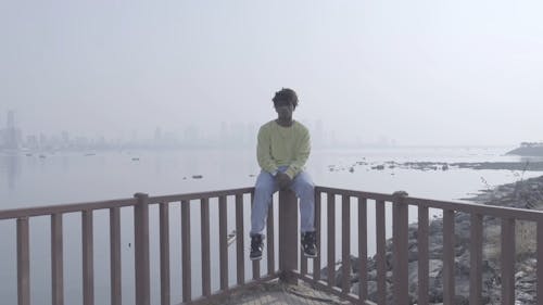 A Man Sitting on a Viewing Deck by the Harbor