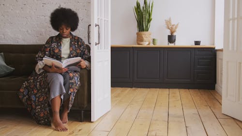 Woman Sitting on a Sofa Reading a Magazine