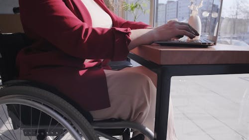 A Woman on a Wheelchair Typing on the Laptop