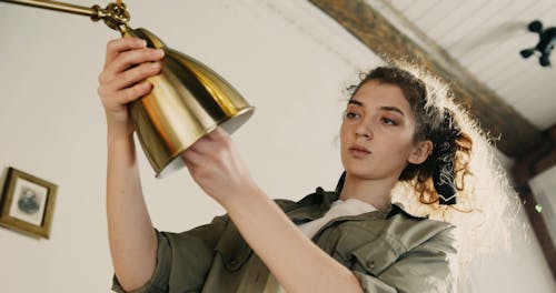 A Woman Changing The Light Bulb Of A Lamp Shade