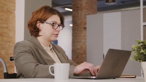 A Woman Drinking Coffee While Using Her Laptop