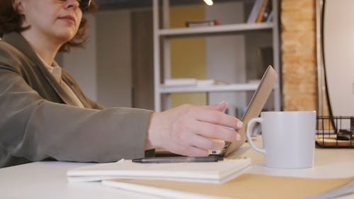 A Woman Drinking Coffee While Using her Laptop