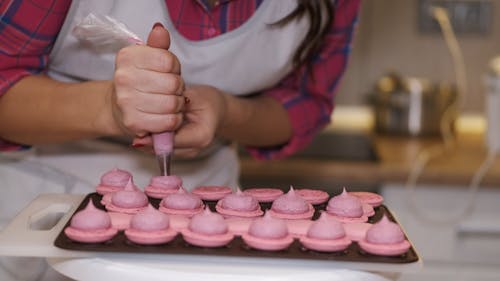 Woman Putting Icing On Pink Pies
