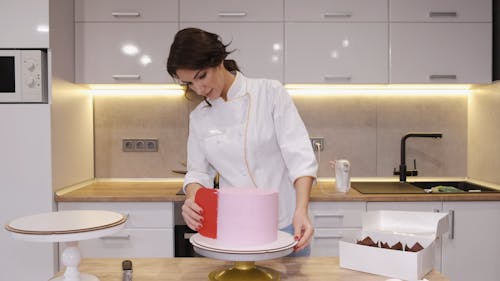A Woman Flattening the Cake Frosting