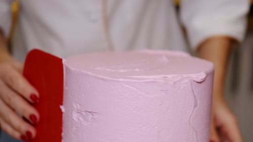 A Person Flattening the Cake Frosting