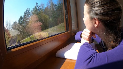 A Woman Looking Outside The Widow Enjoying The Forest View