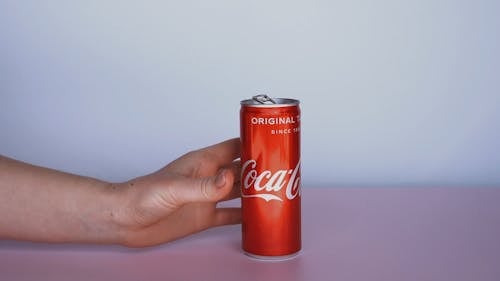 A Person Hand Cashing An Empty Coca-Cola Can