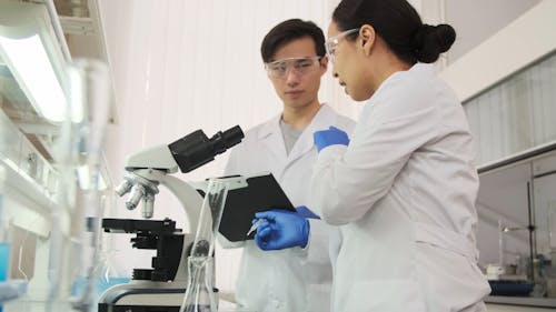 A Woman Explaining Something After Looking Through the Microscope