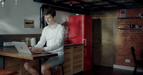 A Man Using His Laptop And Cellphone While Staying At Home