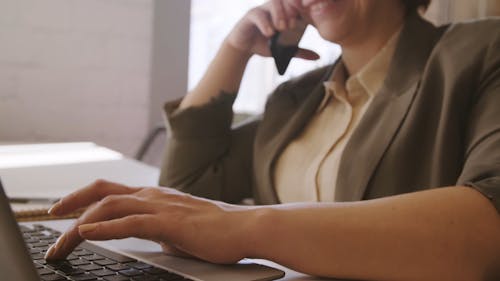 A Woman on a Phone Call Using Her Laptop