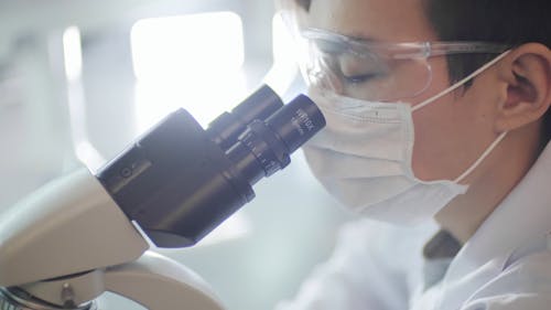 A Doctor Doing A Test Using A Microscope