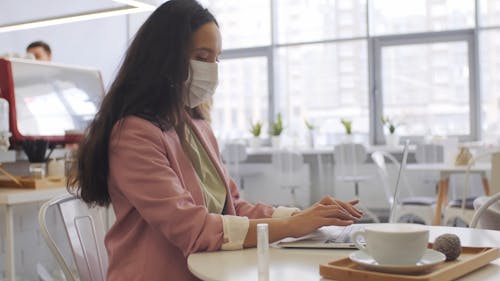 A Woman Sanitizing Her Hand While Working With A Laptop 