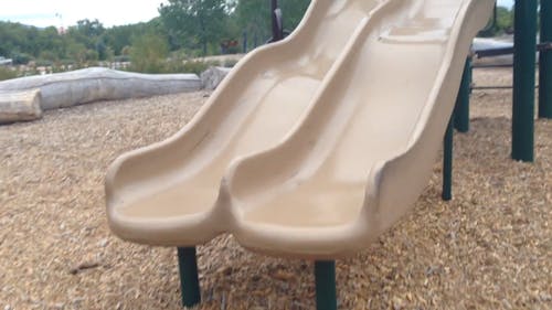 A Little Girl Playing With The Park Playground Slides