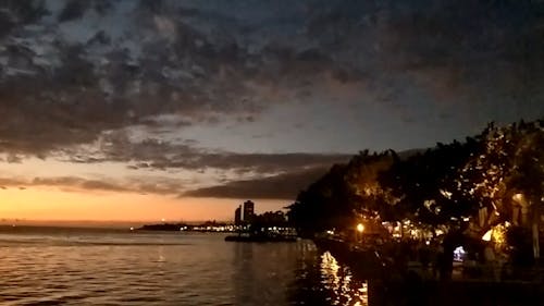 People Enjoying Th Sunset Colors From The Sea Bay