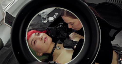 A Woman Smiling While Getting A Tattoo