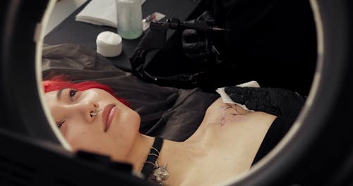 A Woman Lying Motionless During A Tattoo Session
