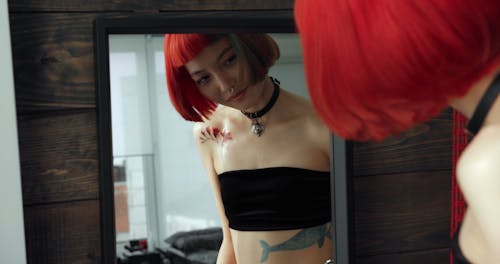 A Woman Looking At Her New Tattoo On A Mirror