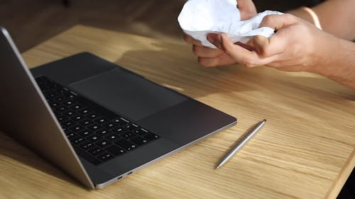 A Person Throwing Crumpled Paper on Laptop