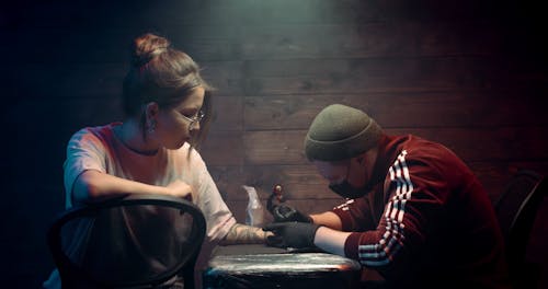 A Tattoo Artist In Session With A Customer In Getting A Hand Tattoo