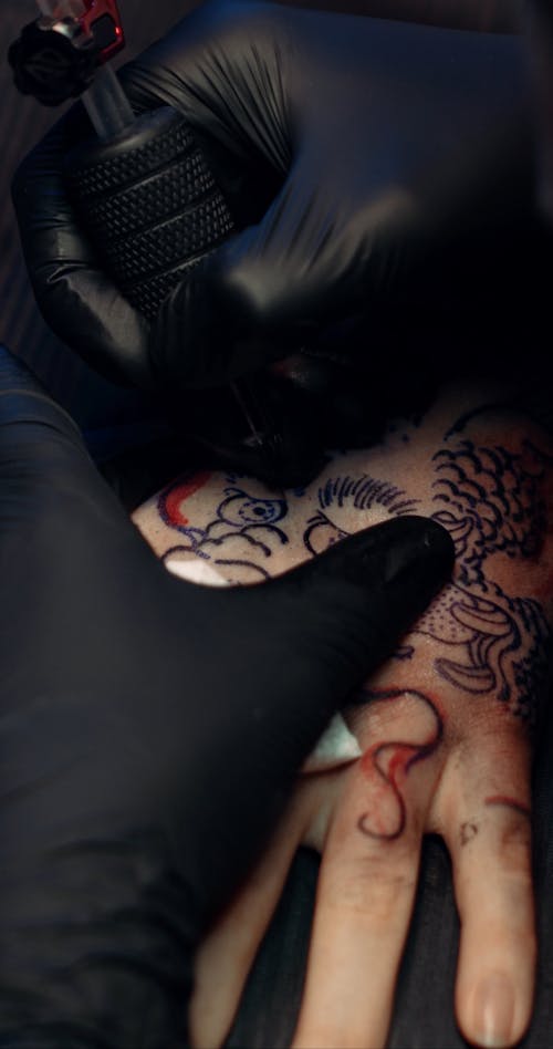 A Tattoo Artist Giving A Customer A Hand Dragon Tattoo 
