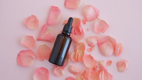 Brown Bottle Surrounded With Pink Petals