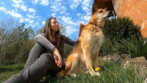 A Woman And Her Dog Sitting On A Grass