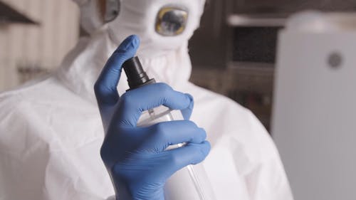 Person in Protective Suit Spraying Sanitizer