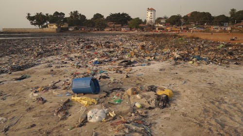 Young Men Playing Football In A Filthy Beach