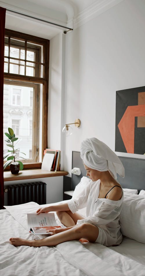 A Woman Reading A Magazine While Seated In Bed