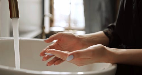 A Woman Washing Her Hands With Water And Soap