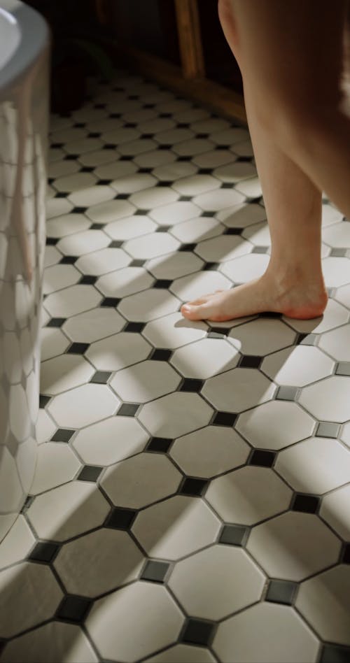 A Woman Walking On The Bathroom Floor Tiles