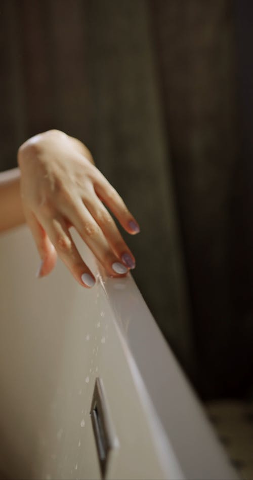 A Woman Running Her Fingers On A Bathtub Edge