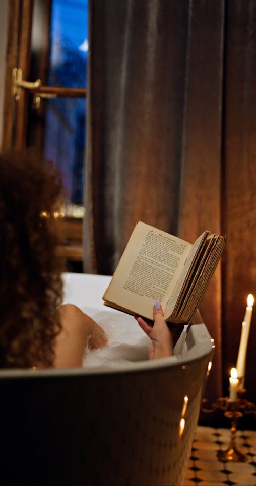 A Woman Reading A Book In A Bath Tub