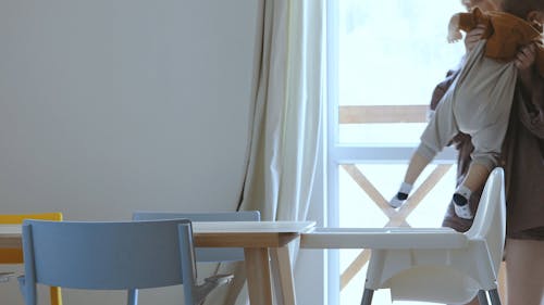 Mother Sitting her Child at the Table