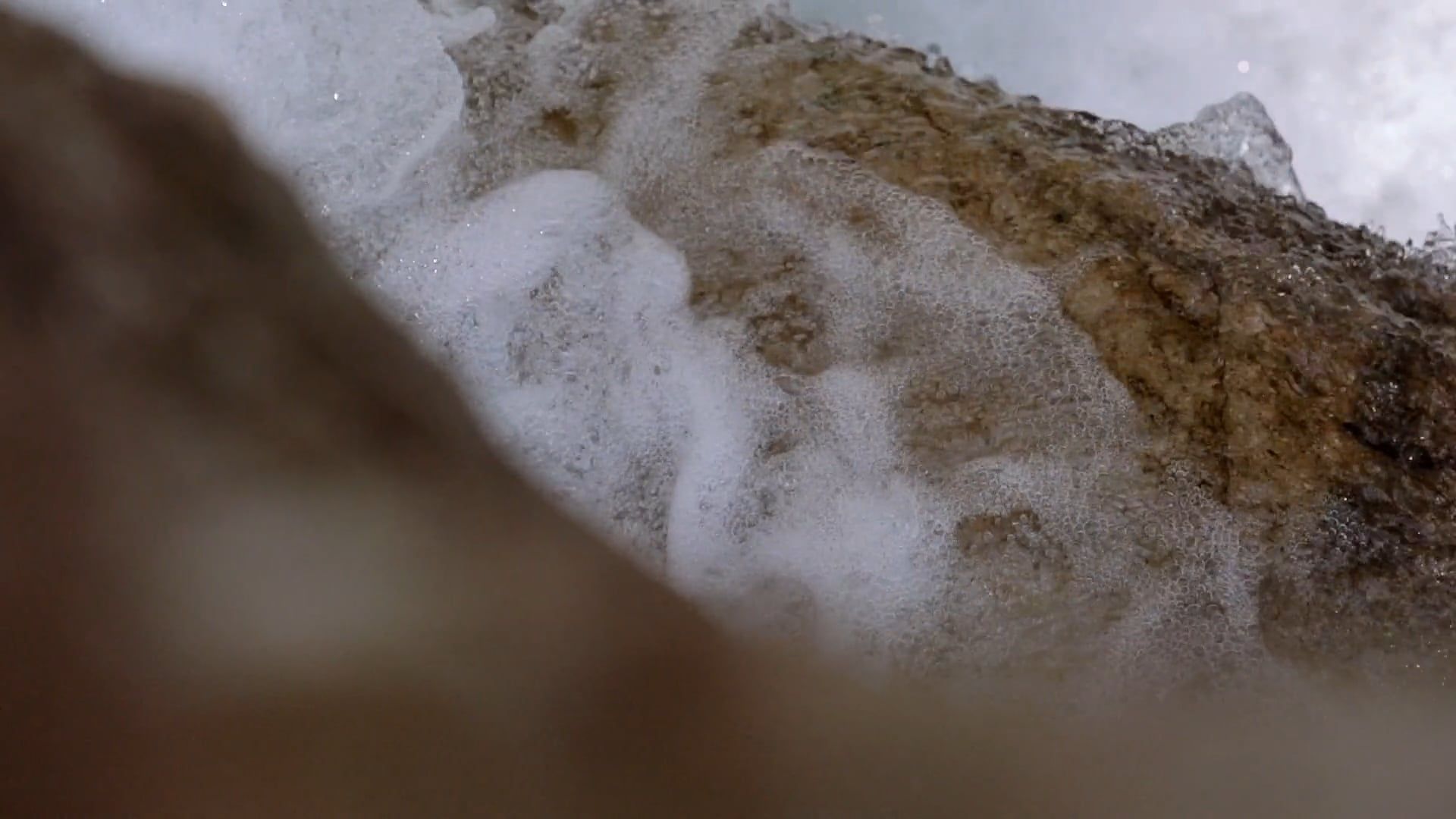 slow motion shot of waves crashing on a big rock 4173995