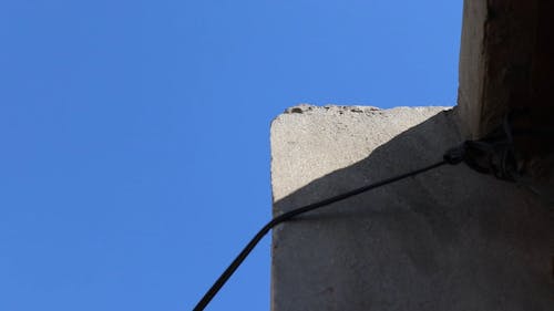A Rope Tied On Gray Concrete Wall Under Blue Sky