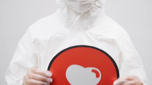 A Person in a Protective Suit Holding a Heart Logo