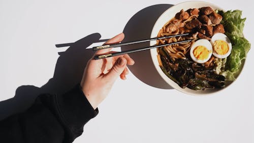 Eating A Noodle Soup Dish With Chopsticks