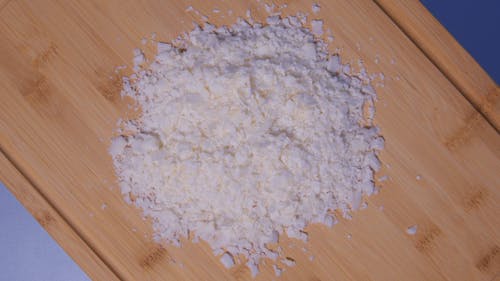 Revolving Shot of Grated Cheese on a Wooden Chopping Board