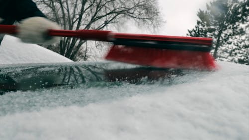 Person Brushing Of Snow On Vehicle