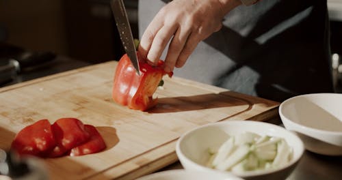 A Chef Slicing A Red Bell Pepper With A Knife