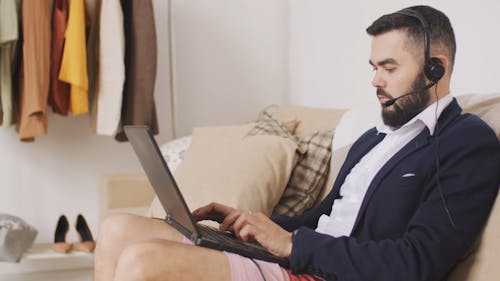 A Man Using A Laptop With Headset Is Working At Home