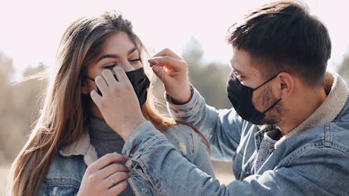 Man Adjusting Woman's Face Mask