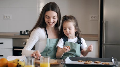 A Mother And Daughter Eating Their Homemade Cookies