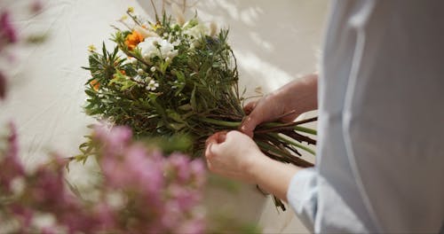 A Person Tying A Bouquet Of Flowers