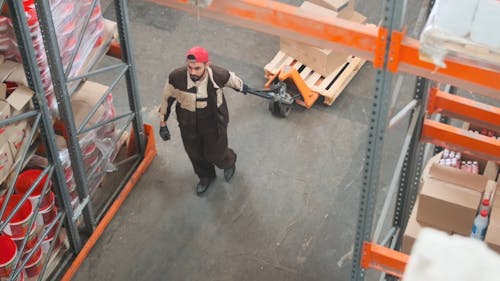 A Man Pulling a Pallet Crate Full of Stocks